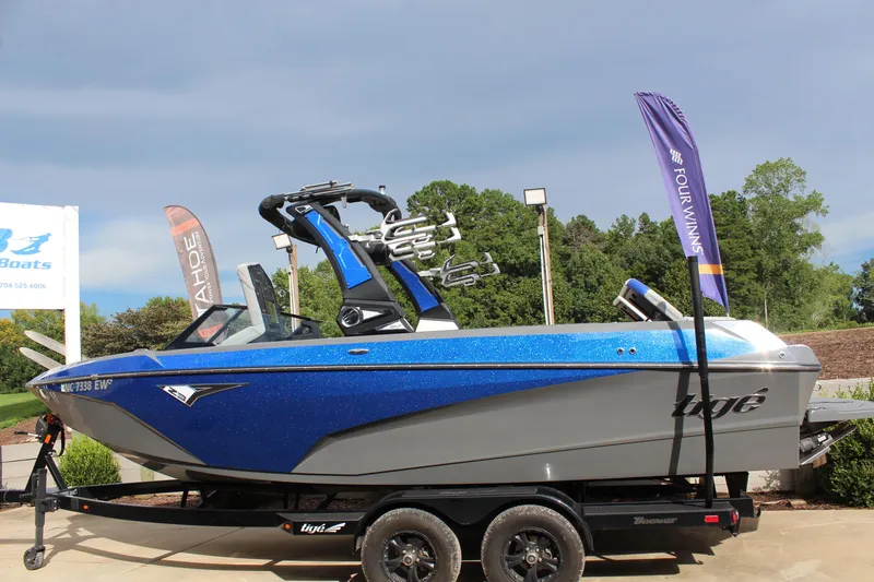 Slide: The Image of 2022 Tigé Z3 boat on trailer, blue and silver, displayed outdoors with flags. - 6