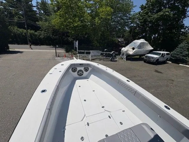 Slide: The Image of 2025 Latitude Tournament Boats 25, spacious deck, parked outdoors, surrounded by trees and vehicles. - 14