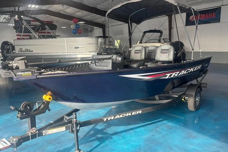 Slide: The Image of 2026 Tracker PG V16 SC boat in showroom, blue hull, on trailer. - 2