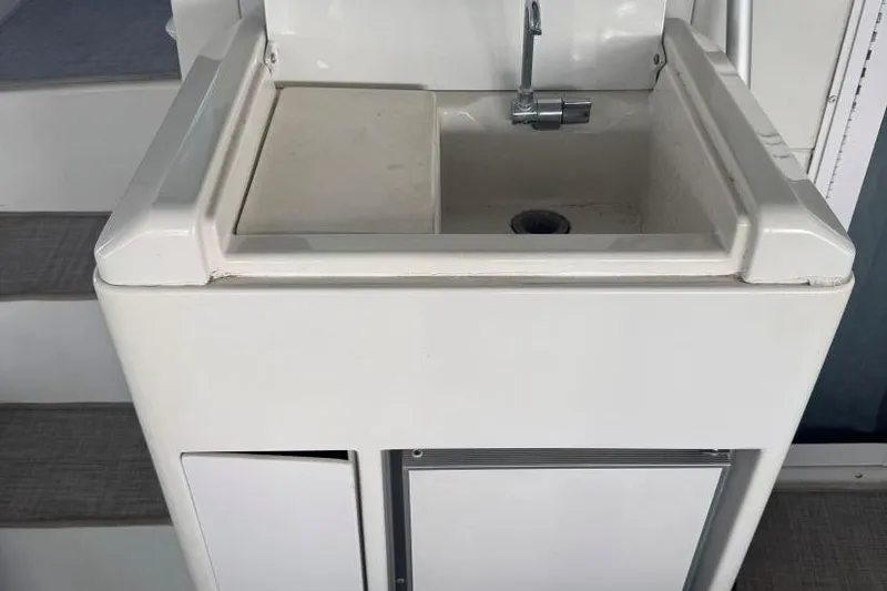 Slide: The Image of 1998 Carver 405 Motor Yacht sink with faucet, white cabinetry, and steps in background. - 19