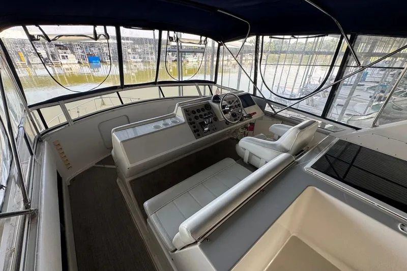 Slide: The Image of 1998 Carver 405 Motor Yacht helm with steering wheel, controls, and seating, docked at marina. - 21