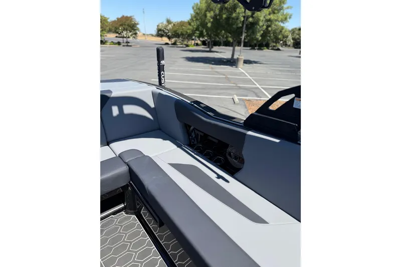 Slide: The Image of 2025 MasterCraft NXT22 boat interior with gray seating in a parking lot. - 13