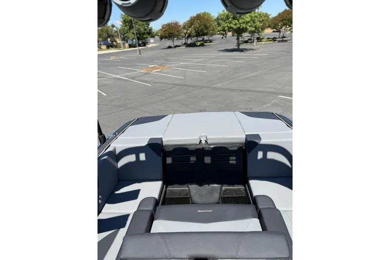 Slide: The Image of 2025 MasterCraft NXT22 boat interior with gray seating in an empty parking lot. - 14