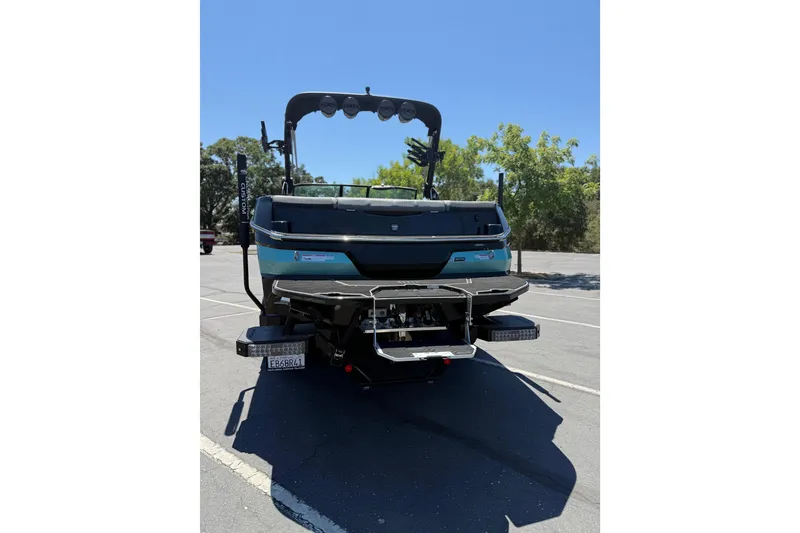 Slide: The Image of 2025 MasterCraft NXT22 boat rear view in parking lot, showcasing sleek design and features. - 2