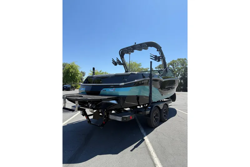 Slide: The Image of 2025 MasterCraft NXT22 boat on trailer in parking lot, clear blue sky. - 3
