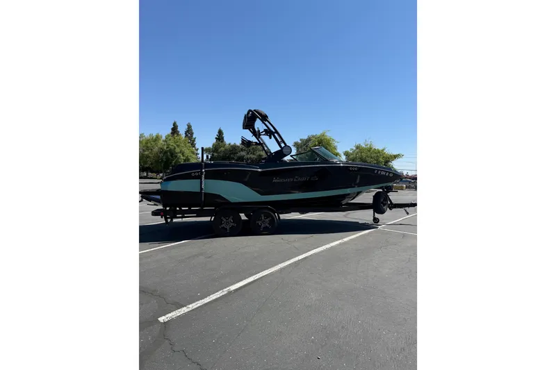 Slide: The Image of 2025 MasterCraft NXT22 boat on trailer in parking lot under clear blue sky. - 4