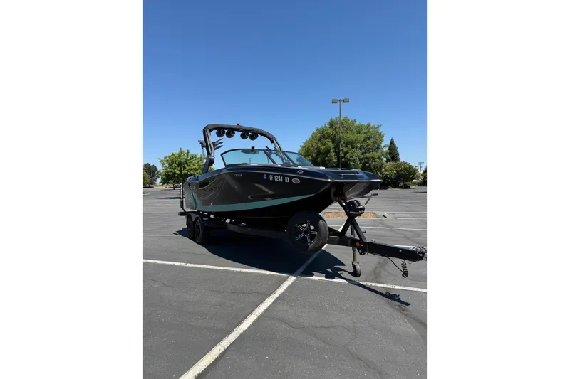 Slide: The Image of 2025 MasterCraft NXT22 boat on trailer in parking lot under clear blue sky. - 5