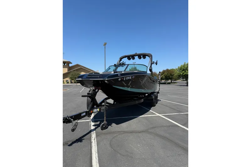 Slide: The Image of 2025 MasterCraft NXT22 boat on trailer in parking lot under clear blue sky. - 6