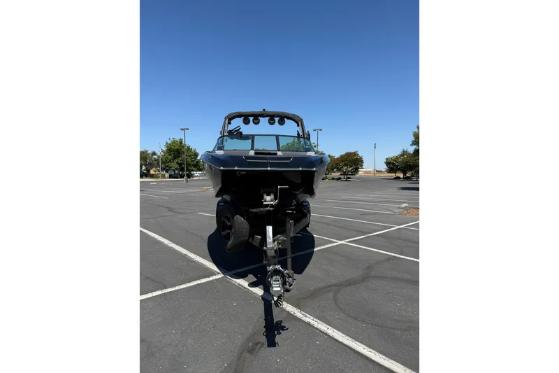 Slide: The Image of 2025 MasterCraft NXT22 boat on trailer in parking lot, clear blue sky. - 7