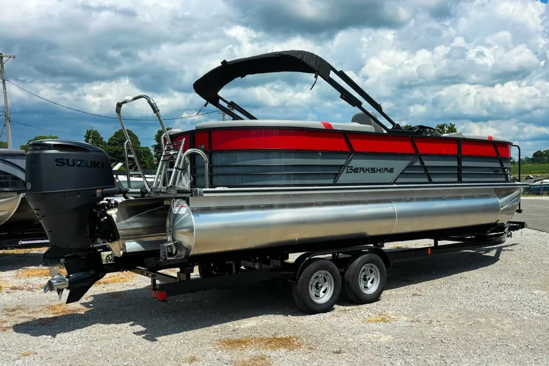 Slide: The Image of 2026 Berkshire 24RFX CTS pontoon boat with Suzuki engine on trailer, under cloudy sky. - 0