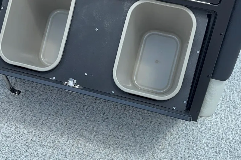 Slide: The Image of Berkshire 24RFX CTS 2026 boat storage compartments with beige bins on gray carpet. - 13