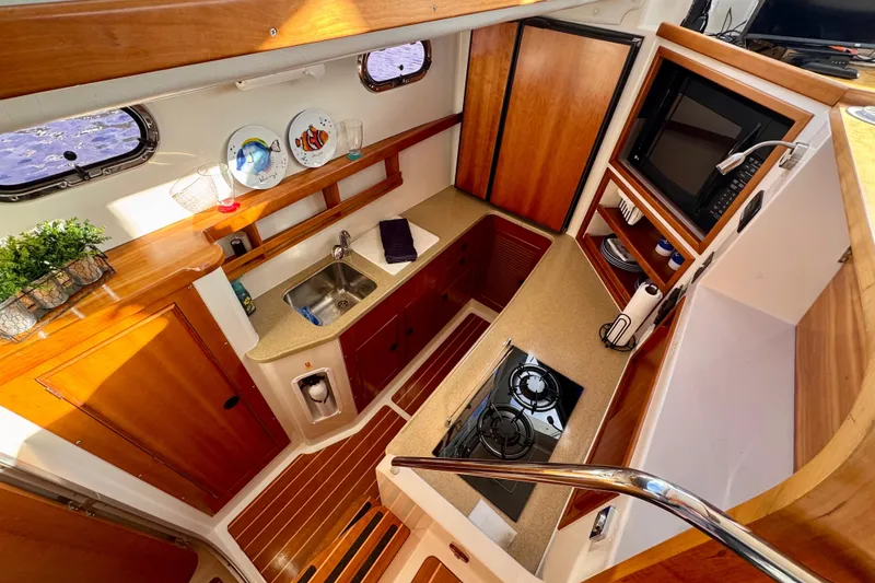 Slide: The Image of 2006 PDQ PowerCat interior kitchen with wooden cabinetry, stove, sink, and decorative plates. - 10