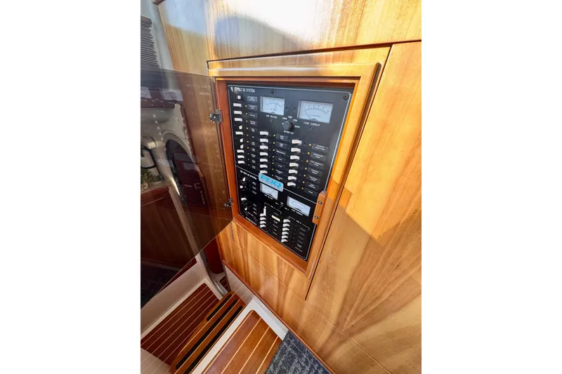Slide: The Image of Electrical panel on 2006 PDQ PowerCat boat, featuring gauges and switches in a wooden enclosure. - 12