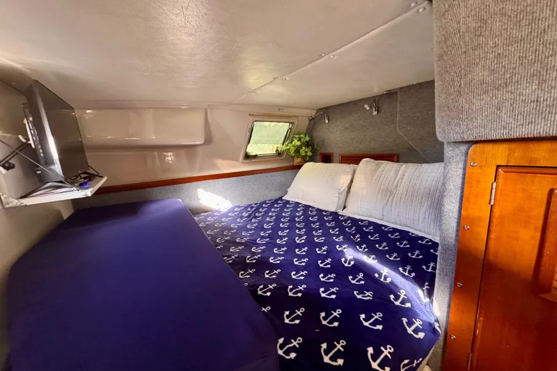 Slide: The Image of Cozy cabin interior of 2006 PDQ PowerCat with anchor-themed bedding and small window. - 15