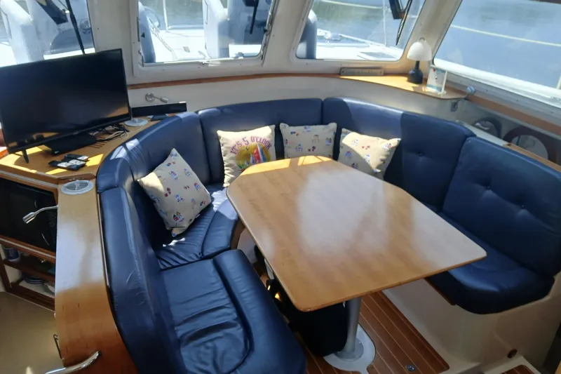 Slide: The Image of 2006 PDQ PowerCat interior with blue seating, wooden table, and TV setup. - 4