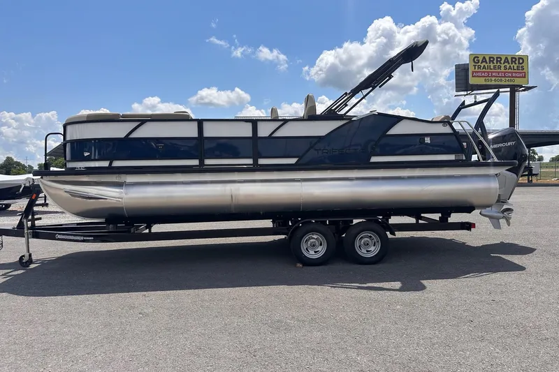 Slide: The Image of 2026 Trifecta 23 ULE SS pontoon boat on trailer under blue sky. - 17