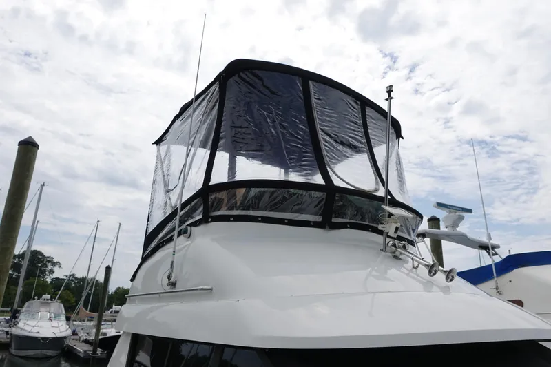 Slide: The Image of 1993 Silverton 31 Convertible boat with clear enclosure, docked at marina under cloudy sky. - 2