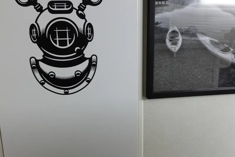 Slide: The Image of Wall art featuring a vintage diving helmet and framed kayak photograph. - 23