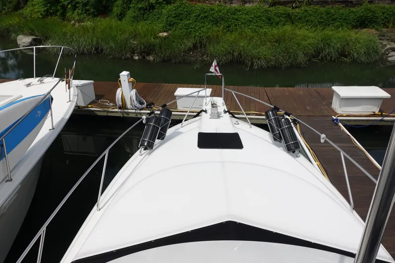 Slide: The Image of 1993 Silverton 31 Convertible docked, view from bow, surrounded by greenery. - 9