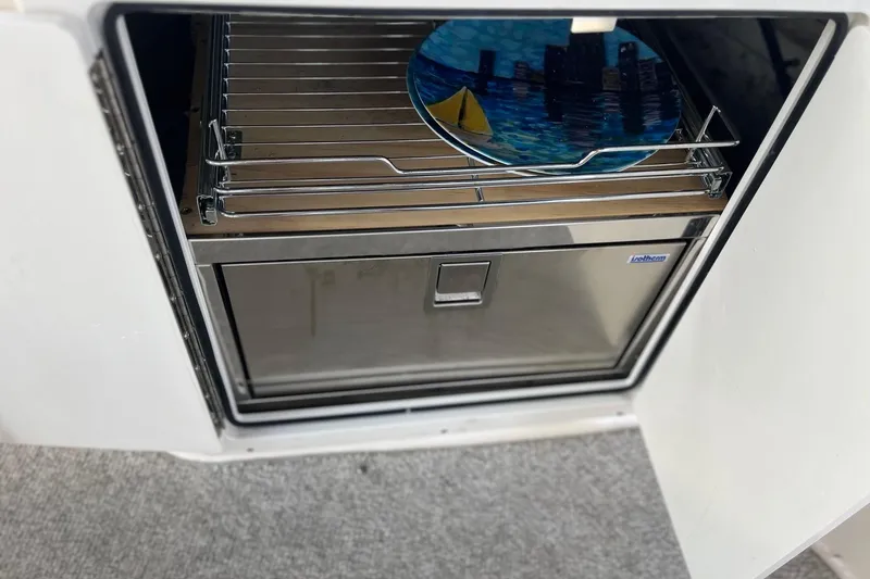 Slide: The Image of 2004 Rinker Fiesta Vee 270 boat interior with white seating and wooden table. - 10