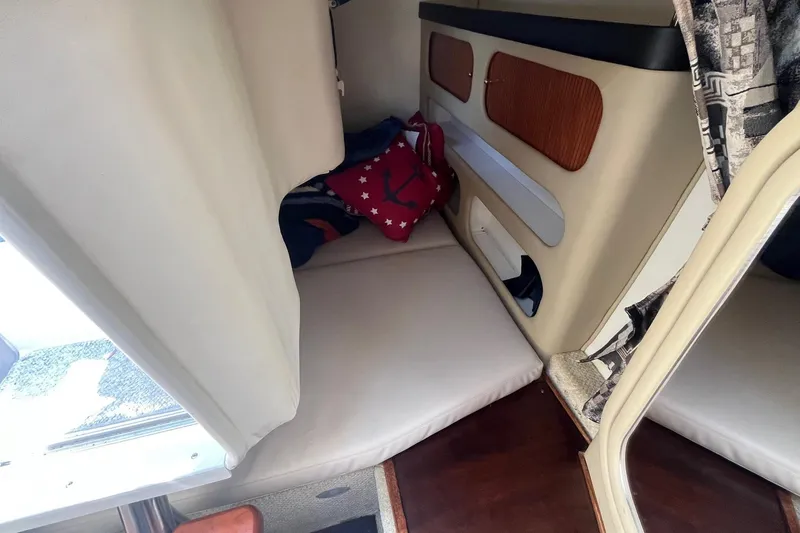 Slide: The Image of 2004 Rinker Fiesta Vee 270 cabin interior with cushioned seating and storage compartments. - 18