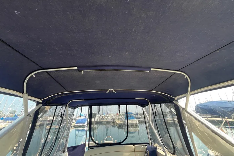 Slide: The Image of 2004 Rinker Fiesta Vee 270 cabin interior with round wooden table and nautical-themed cushions. - 4