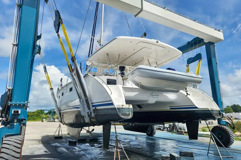 Slide: The Image of 2019 Antares 44GT catamaran lifted by crane in a boatyard under blue sky. - 20