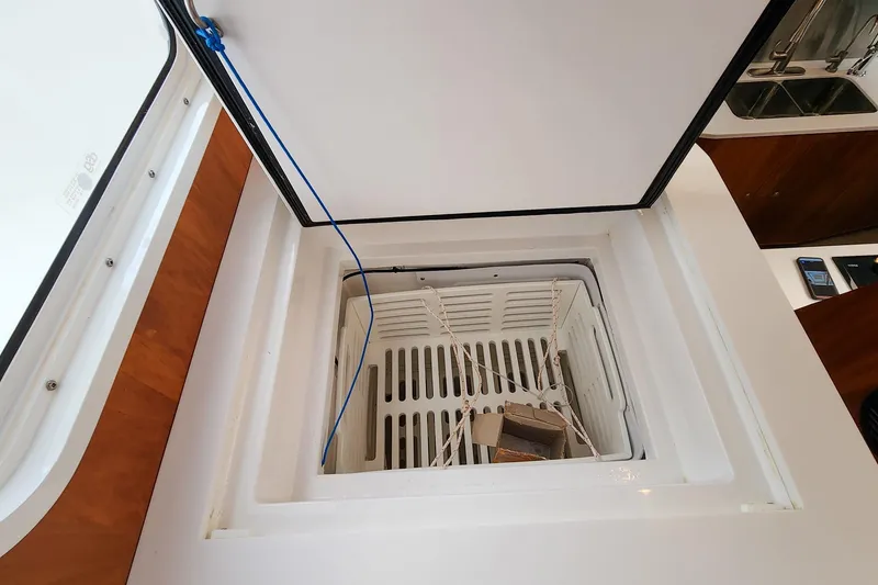 Slide: The Image of Open storage compartment on 2019 Antares 44GT boat, featuring a white interior and blue cord. - 37