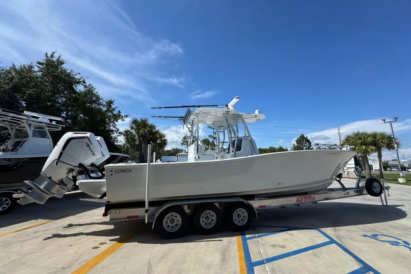 Slide: The Image of 2025 Conch 33 boat on trailer, parked outdoors under clear blue sky. - 12