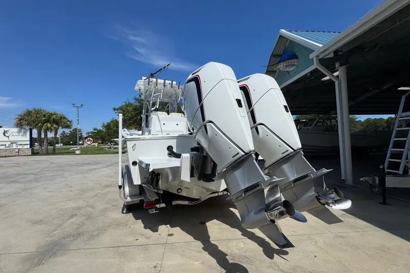 Slide: The Image of 2025 Conch 33 boat with dual outboard motors, parked outdoors under clear blue sky. - 17