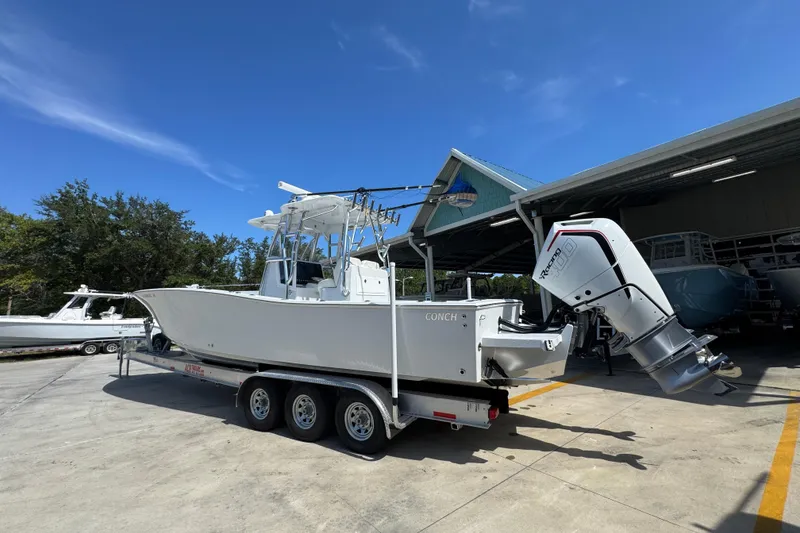 Slide: The Image of 2025 Conch 33 boat on trailer, parked outdoors under clear blue sky. - 19