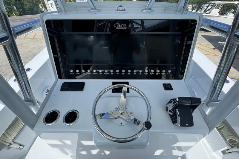 Slide: The Image of 2025 Conch 33 boat dashboard with steering wheel, controls, and navigation display. - 35