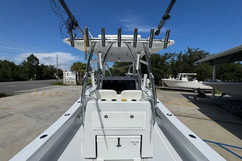 Slide: The Image of 2025 Conch 33 boat with T-top and rod holders, parked outdoors under clear sky. - 40