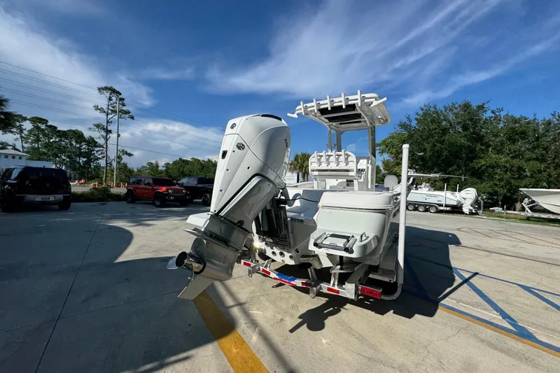 Slide: The Image of 2026 Caymas 24 HB boat with outboard motor on a trailer, parked outdoors. - 13