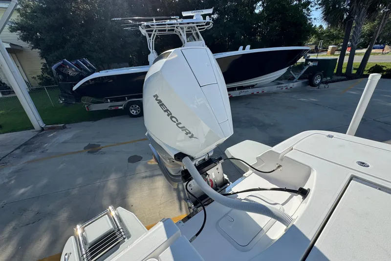 Slide: The Image of 2026 Caymas 24 HB boat with Mercury outboard engine, parked near another boat. - 39