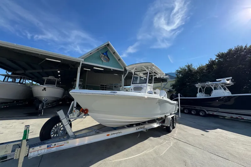Slide: The Image of 2026 Caymas 24 HB boat on trailer under clear blue sky at marina. - 4