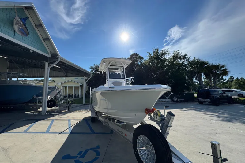 Slide: The Image of 2026 Caymas 24 HB boat on trailer under sunny sky at marina. - 7