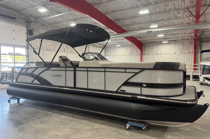 Slide: The Image of 2026 Sylvan L-5 pontoon boat in showroom, featuring sleek design and canopy. - 1