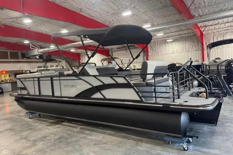 Slide: The Image of 2026 Sylvan L-5 pontoon boat in showroom with red beams and industrial lighting. - 3