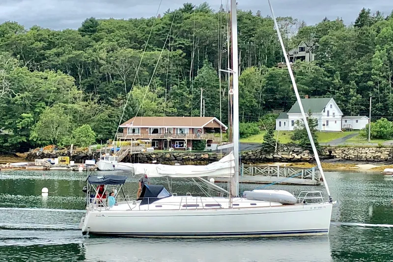 Slide: The Image of 2007 Hanse 400 sailboat cruising near a scenic shoreline with houses and trees. - 2