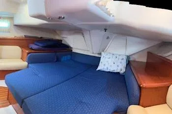 Slide: The Image of Interior of 2005 Jeanneau Deck Salon 43 with blue bedding and wooden accents. - 15
