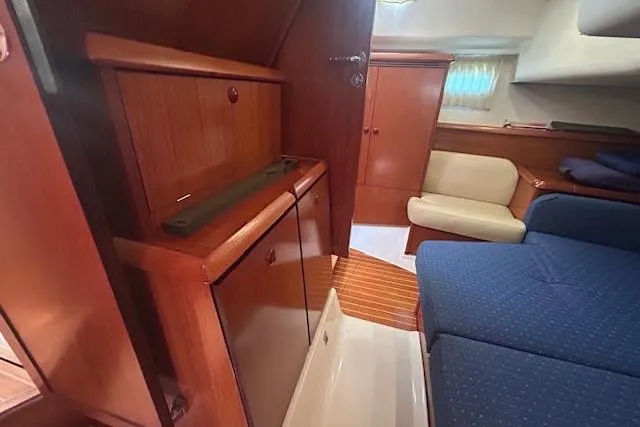 Slide: The Image of Interior of 2005 Jeanneau Deck Salon 43, featuring wooden cabinetry and blue seating. - 21