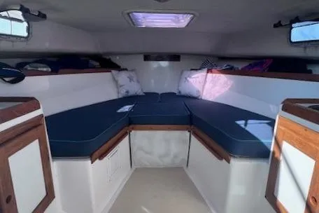 Slide: The Image of 2004 Hunt Yachts Surfhunter 25 cabin interior with blue cushions and wooden accents. - 18