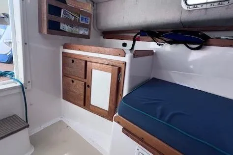 Slide: The Image of 2004 Hunt Yachts Surfhunter 25 interior with wooden cabinetry and blue cushioned seating. - 22