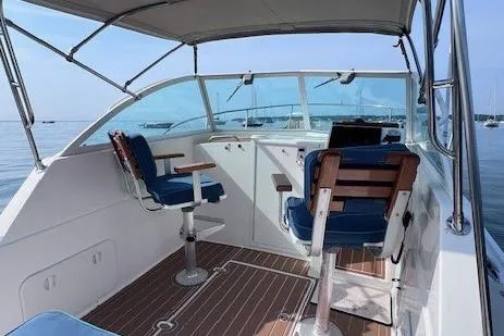 Slide: The Image of 2004 Hunt Yachts Surfhunter 25 cockpit with blue seating and wooden accents on calm water. - 8