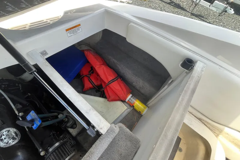 Slide: The Image of Open storage compartment in 2013 Monterey 184FS boat with safety gear and engine visible. - 14