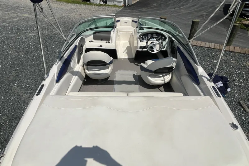 Slide: The Image of 2013 Monterey 184FS boat interior with seating and steering wheel, docked on gravel. - 7