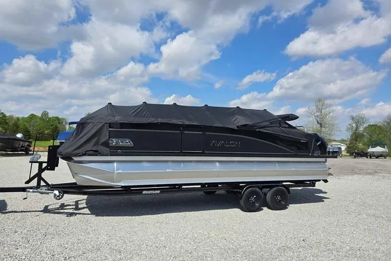 Slide: The Image of 2025 Avalon Catalina QUAD LOUNGER SHIFT pontoon boat on trailer, covered, outdoors. - 2