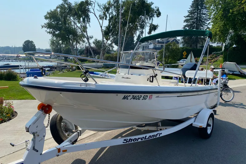 Slide: The Image of 2001 Boston Whaler 18 Dauntless boat on trailer, parked near waterfront homes. - 2