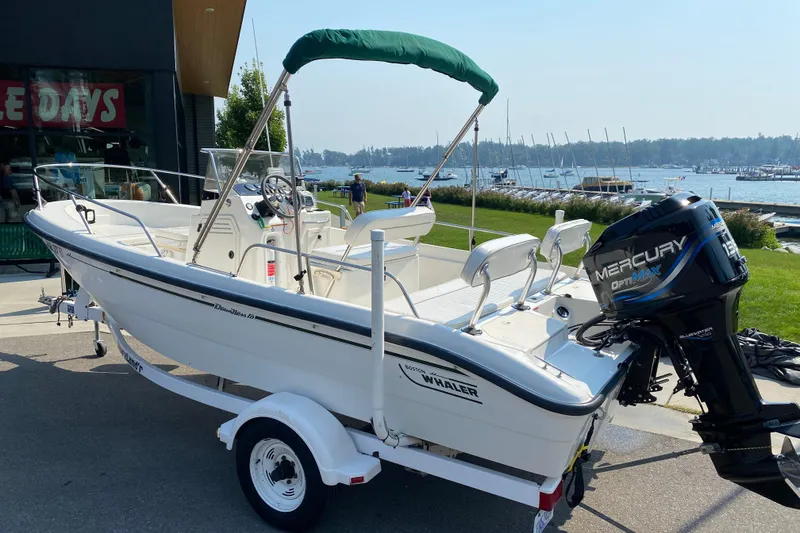 Slide: The Image of 2001 Boston Whaler 18 Dauntless boat with Mercury engine, docked near a marina. - 4